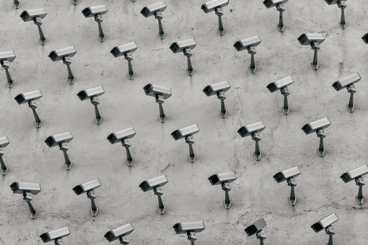 a pattern of CCTV surveillance cameras on a wall, all pointing in different directions.